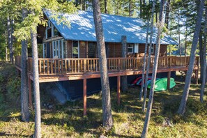 Une cabane dotée d’une terrasse en bois et d’un toit bleu, entourée d’arbres.