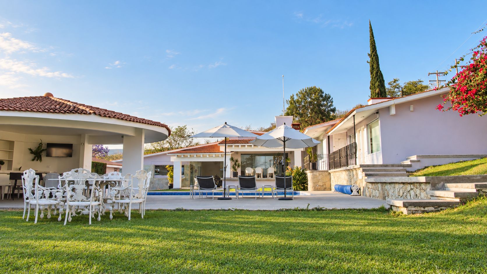 A modern house with a swimming pool, outdoor seating, and a well-maintained lawn.