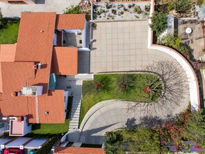 A residential building with a red-tiled roof, a paved driveway, and a landscaped garden with trees and shrubs. - Mansion Maria - 5 Luxury Suites & Heated Pool (San Felipe del Agua)