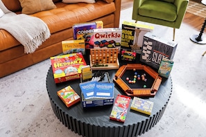 Verschillende gezelschapsspellen en speelgoed, netjes gerangschikt op een ronde salontafel in een woonkamer.