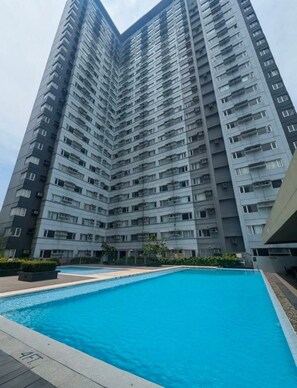 Ein Hochhaus mit Wohnungen und einem Schwimmbad im Vordergrund.