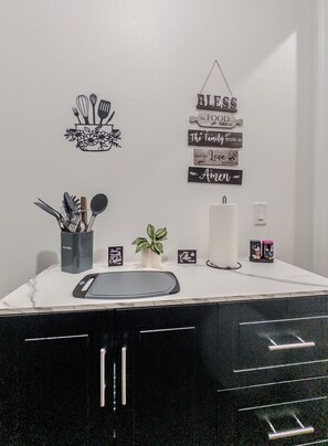 Una encimera de cocina con una cafetera, una planta y diversos utensilios de cocina.