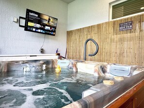 Ein Whirlpool mit einer Holzwand und einem darüber montierten Fernseher.
