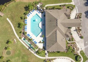 An aerial view of a property with a swimming pool, lounge chairs, and a large building with a unique roof design. - The Disney Oasis - Your Disney Day! - Your Spa Night! (Kissimmee)
