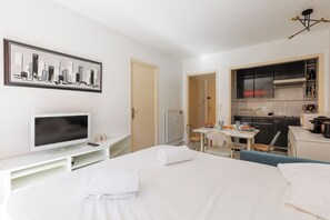 A hotel room with a bed, a TV, a desk, and a kitchenette. - Upstays Cosy T2 32m² with balcony and AC (Cannes)