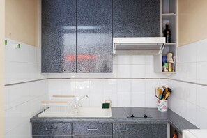 A kitchen with a grey marble countertop, a sink, a cabinet with a built-in range hood, and a spice rack. - Upstays Cosy T2 32m² with balcony and AC (Cannes)