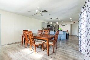 A dining area with a wooden table and chairs, a ceiling fan, and a kitchen in the background. - 4-Bedroom Lehigh Acres Getaway with Private Pool & Spa (Lehigh Acres)