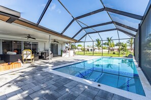 A modern outdoor pool area with a covered patio, seating, and a view of the surrounding landscape. - 4-Bedroom Lehigh Acres Getaway with Private Pool & Spa (Lehigh Acres)