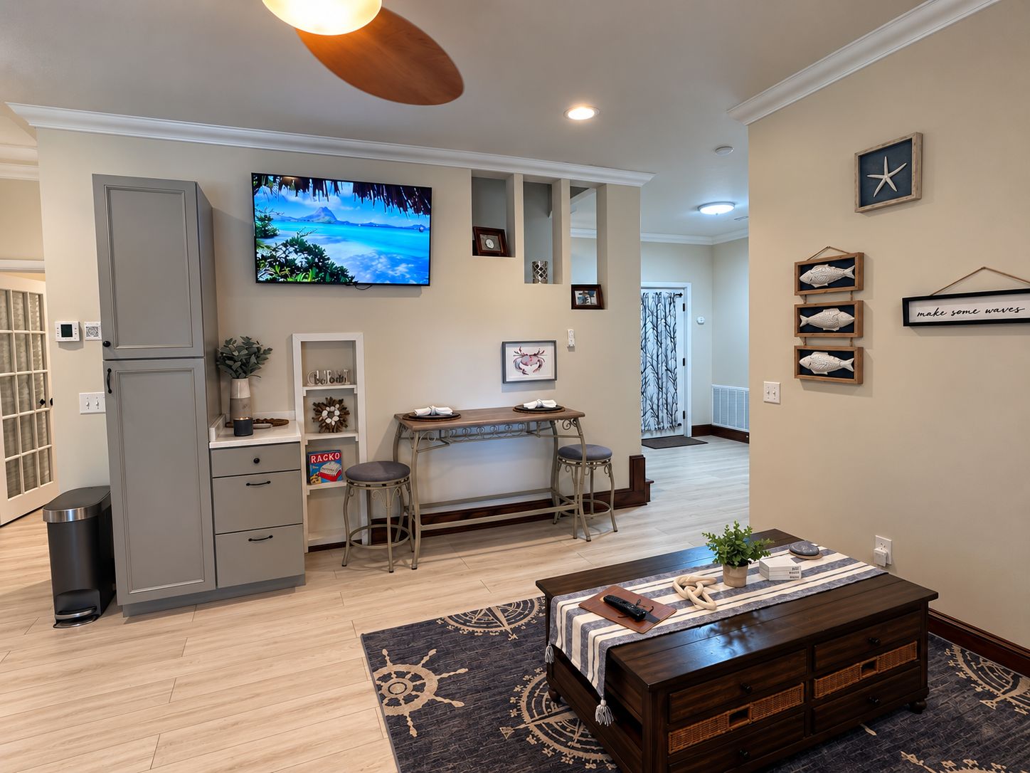 A modern kitchen with a flat-screen TV, a dining area with a bar stool, and a cozy seating area with a coffee table.