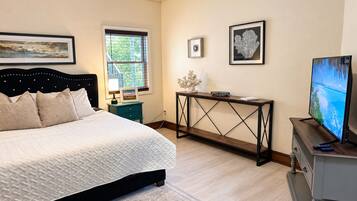A bedroom with a bed, a desk, a television, and artwork on the walls.