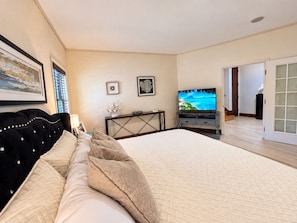 Een slaapkamer met een groot bed, een televisie en een bureau met een computer.
