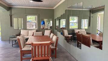 A room with a ceiling fan, a dining table with chairs, a sofa, and a large mirror on the wall.