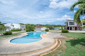 A residential area with a swimming pool, modern houses, and a small building with a red roof. - Brisas de Tamarindo | Pool in Front (Tamarindo)