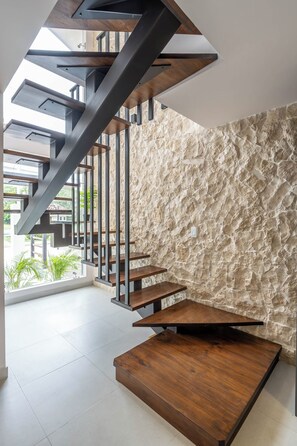 A modern staircase with wooden steps and metal railings, leading to a high ceiling with skylights. - Brisas de Tamarindo | Pool in Front (Tamarindo)