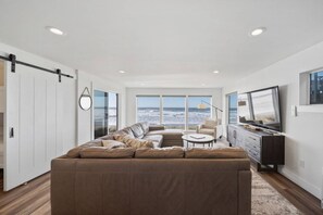 A modern living room with a large sectional sofa, a coffee table, and a TV. - Unforgettable Ocean Views From Home and Hot Tub, Fire Pit, Chef's Gourmet Kitchen, Steps From Beach (Rockaway Beach)