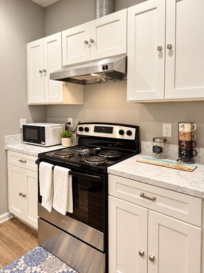 A kitchen with white cabinets, a stainless steel stove, a microwave, and a coffee maker. - 3-bedroom house in amazing Fort Walton Beach within 6 minutes from the beach. (Fort Walton Beach)