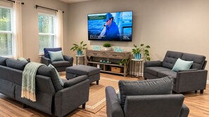 A living room with grey sofas, a flat-screen TV, and a wooden coffee table. - 3-bedroom house in amazing Fort Walton Beach within 6 minutes from the beach. (Fort Walton Beach)