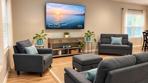 A living room with two grey sofas, a coffee table, a TV mounted on the wall, and a wooden cabinet with decorative items. - 3-bedroom house in amazing Fort Walton Beach within 6 minutes from the beach. (Fort Walton Beach)
