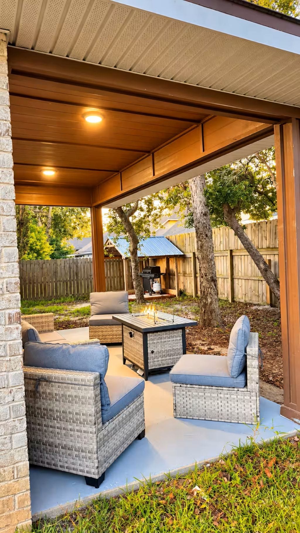 An outdoor patio with wicker furniture, a grill, and a covered area.