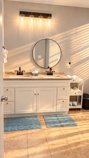 Une salle de bain avec un double lavabo, un miroir rond et un porte-serviettes.
