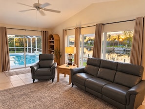 Ein Wohnzimmer mit Blick auf einen Pool, einem Deckenventilator und einem Sofa.