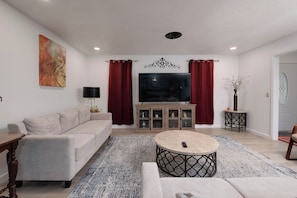 A modern living room with a sofa, TV, and a coffee table. - The Crew House! Spacious 4-bedroom & 3-Bathrooms with 7 Beds! (Amarillo)