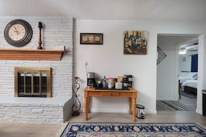 A room with a fireplace, a coffee maker, a framed picture, and a bed in the adjacent room. - The Crew House! Spacious 4-bedroom & 3-Bathrooms with 7 Beds! (Amarillo)
