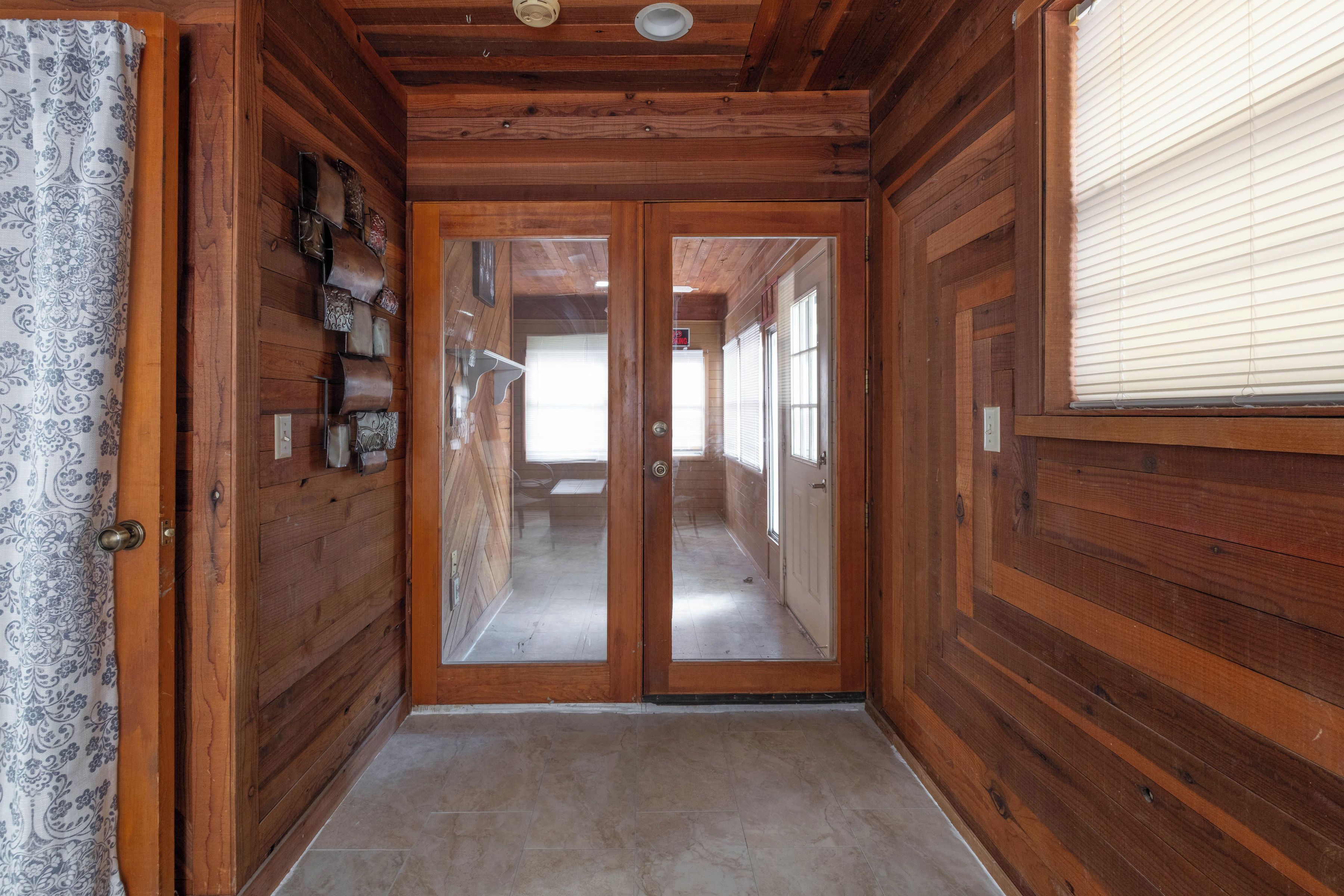 A wooden hallway with a double door leading to a room.