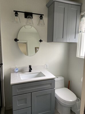 Ein Badezimmer mit einem weißen Waschbecken, einem Spiegel und einer Toilette.