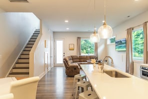 A modern kitchen with a central island, a dining area with a sofa, and a staircase leading to another level. - Charming 4-bedroom house in Charlotte close to Uptown (Charlotte)
