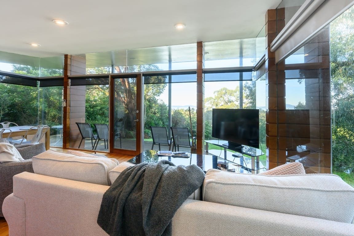 A modern living room with a large TV, comfortable seating, and a glass door leading to an outdoor area.