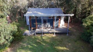 A small, single-story building with a covered porch and a set of stairs leading to the entrance. - Proms Edge - Coastal Banksia Villa (Yanakie)