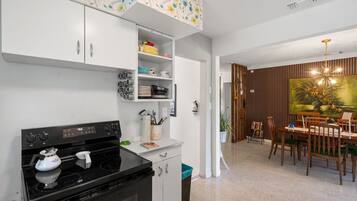 Une cuisine moderne avec des meubles blancs, une cuisinière noire et un coin repas comprenant des chaises et une table en bois.