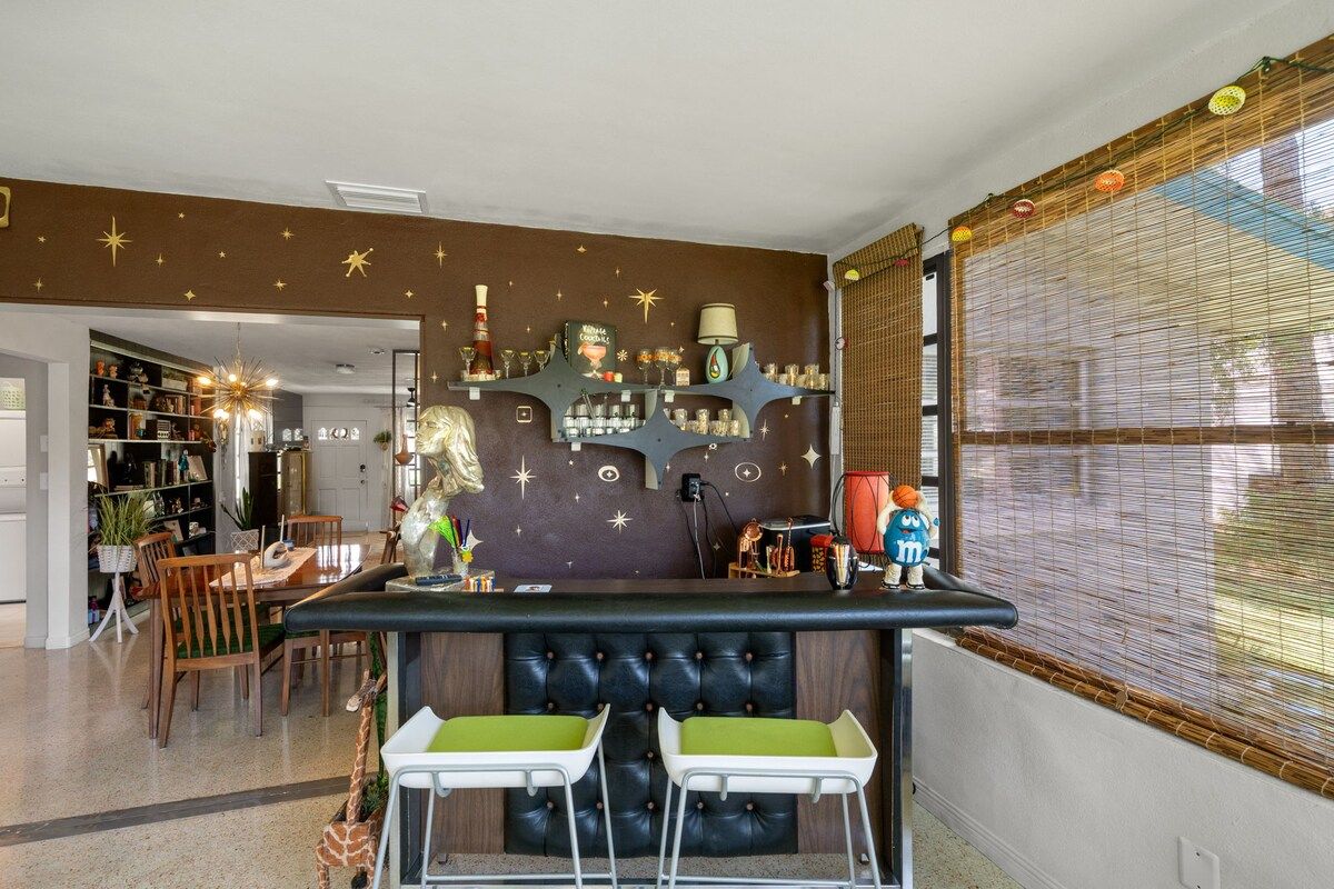 A bar area with a tufted headboard and two green barstools.