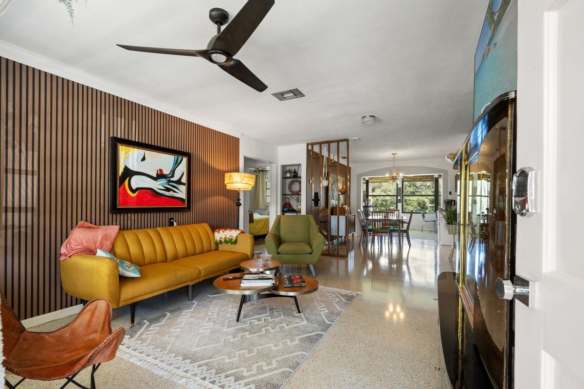 A modern living room with a sofa, armchairs, a coffee table, and a ceiling fan.