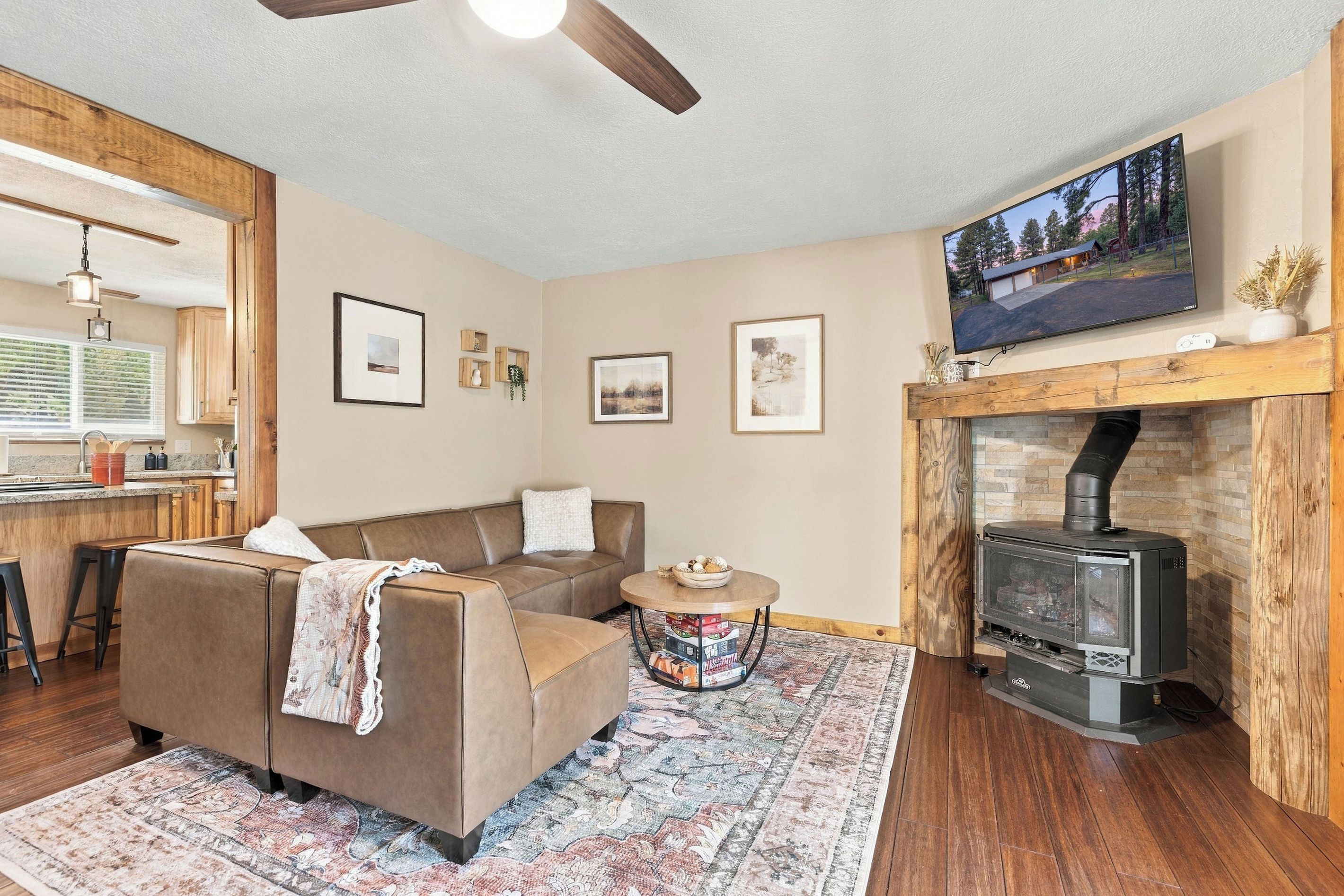 A cozy living room with a fireplace, a sofa, a coffee table, and a television mounted above the fireplace.