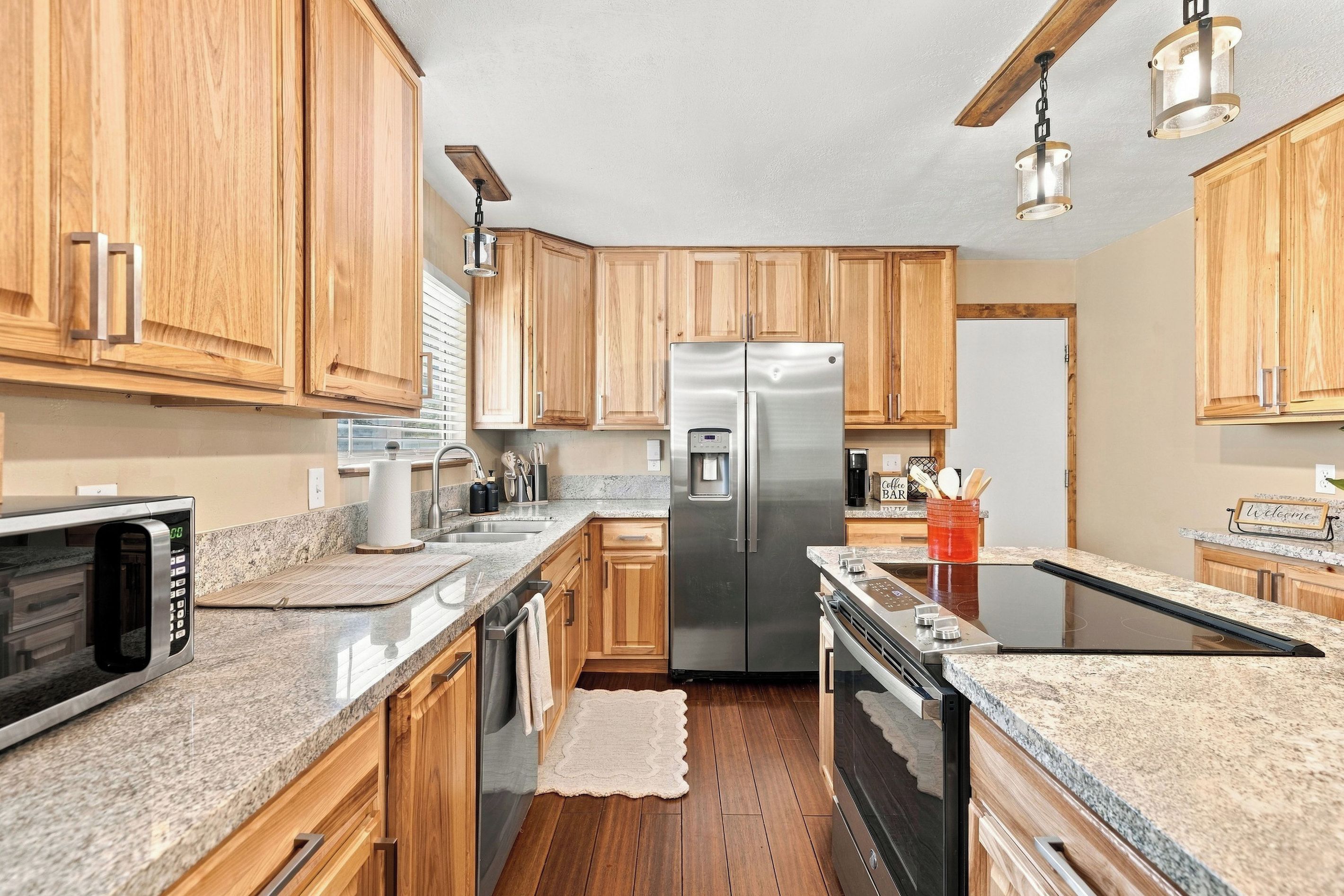 A modern kitchen with wooden cabinets, stainless steel appliances, granite countertops, and a central island.