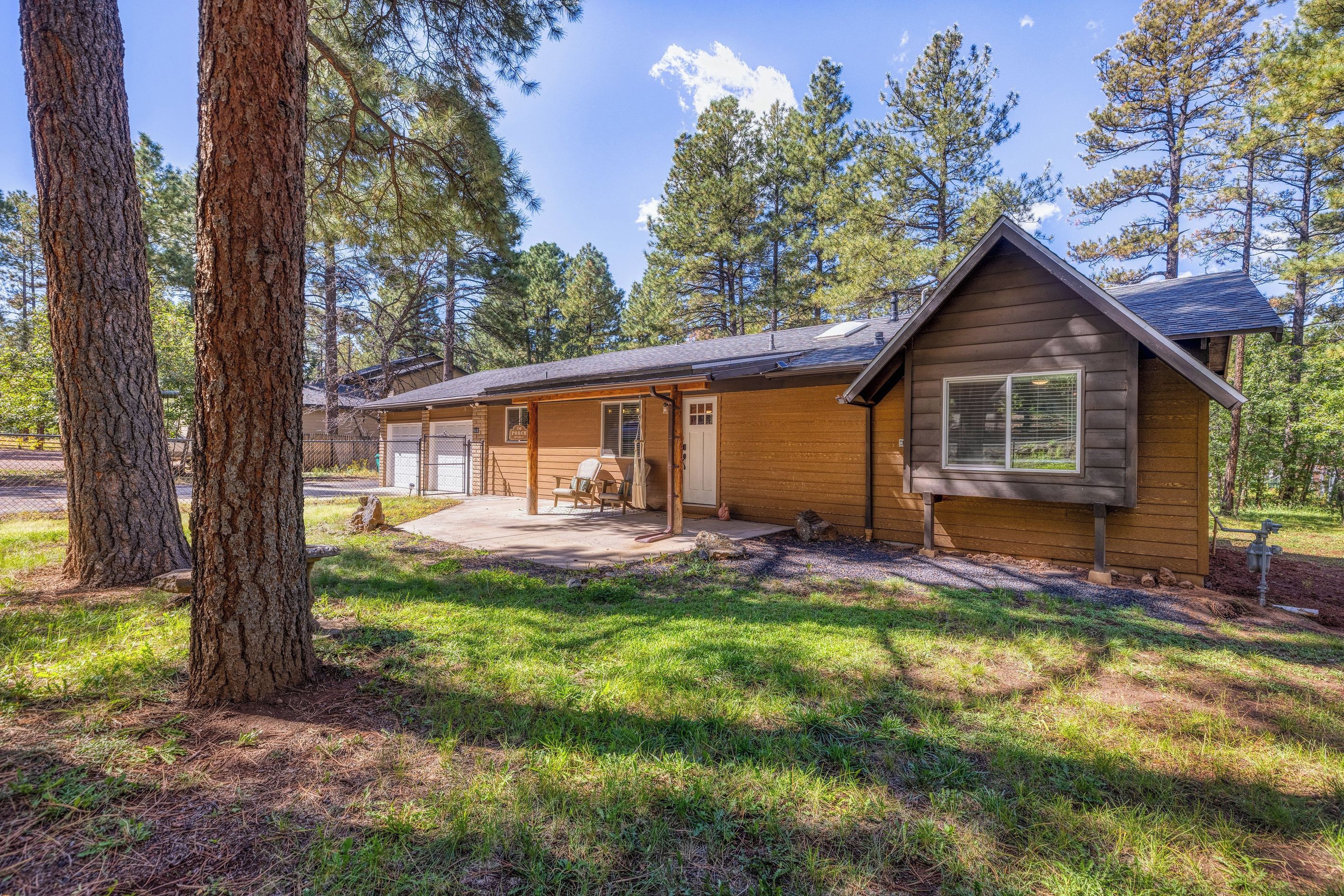 A cabin with a porch, a covered patio, and a small front yard.