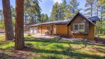 A cabin with a porch, a covered patio, and a small front yard.