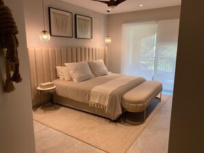 A modern bedroom with a large bed, bedside tables, and a view of the outdoors. - Playa Royale 2204 Beachfront apartment with a balcony and ocean view (Nuevo Nayarit)
