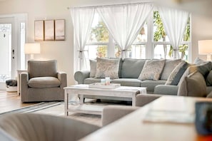A living room with a grey sofa, a matching armchair, and a coffee table. - The Dock House I Gulf Access I Southern Exposure Pool/Spa (Cape Coral)