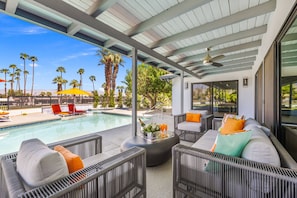A covered outdoor area with a pool, lounge chairs, and a seating area with cushions. - Stunning South Palm Desert Home with Private Pool, Spa & Shadow Mountain Golf Course Views (Palm Desert)