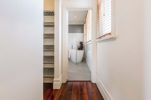 A hallway leading to a bathroom with a bathtub, a shower, and a toilet. - VAQUAY The Marigold In Hawthorn (Hawthorn)