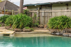 A swimming pool with a wooden fence and tropical plants. - VAQUAY The Marigold In Hawthorn (Hawthorn)