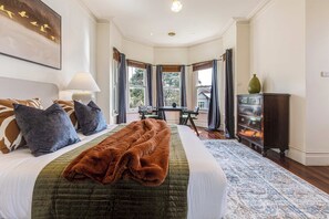 A bedroom with a large bed, a desk, and a view of the outdoors.