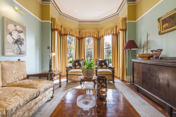 A traditional room with a sofa, armchairs, a coffee table, and a cabinet.