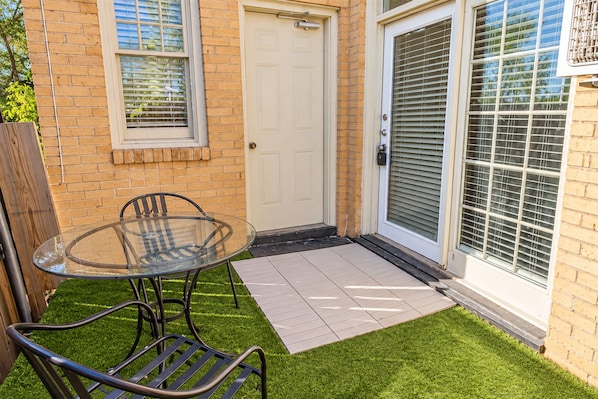 A glass table with chairs, a door, and a window with blinds.