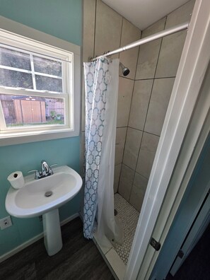 A bathroom with a sink, a window, and a shower area. - Cozy 1-bedroom tiny house in perfect Katy with refreshing AC (Katy)