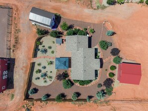 Eine Vogelperspektive eines Wohnhauses mit einem großen Haus, einer Garage und einem durch eine Hecke eingefriedeten Garten.