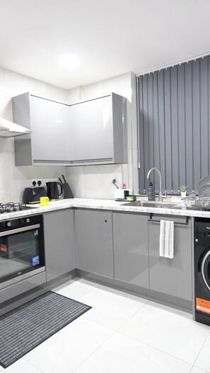 A modern kitchen with grey cabinets, a built-in oven, a dishwasher, and a sink. - Charming Manchester House with 3 Bedrooms (Manchester)